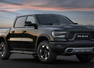 A black Ram pickup truck parked on a road during sunset with city lights in the background, 2K Desktop Wallpaper