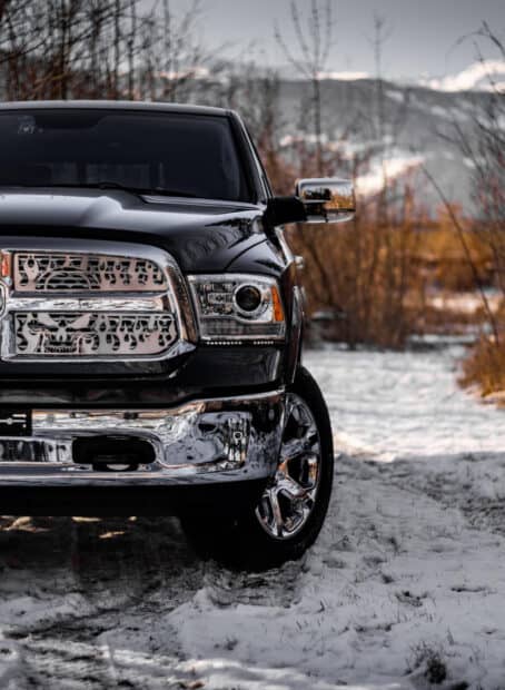 A black Ram pickup is parked on a snowy ground with trees and mountains in the background, HD Mobile Wallpaper