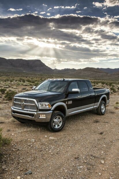 The Ram Pickup is shown resting in a desert landscape with mountains and sun rays breaking through clouds, 2K Phone Wallpaper