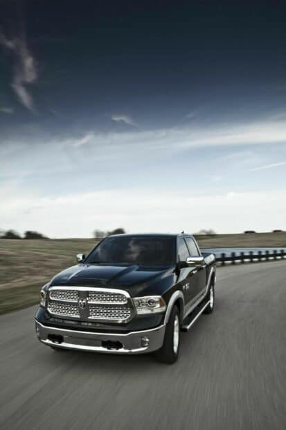 A black Ram truck is driving on a quiet country road under a cloudy sky, HD Mobile Wallpaper