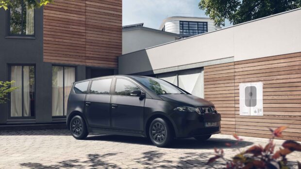 The black Sono Motors car is parked beside the house with wooden panels, HD Desktop Wallpaper