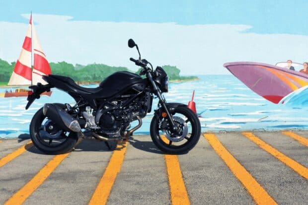A black Suzuki Sv650 is parked on a road near a colorful mural depicting the ocean and sailboats, HD Desktop Wallpaper