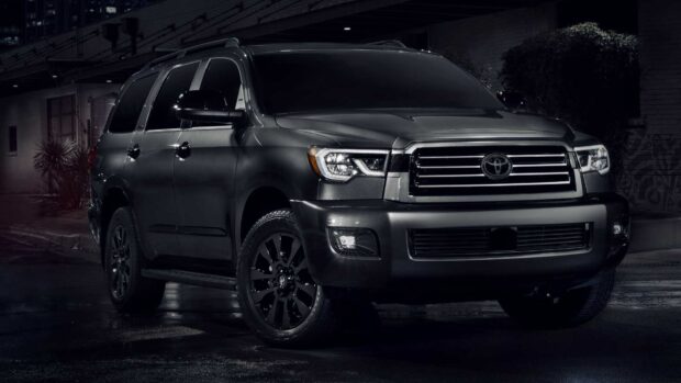 A black Toyota Sequoia is parked on a wet street with city lights in the background, HD Desktop Wallpaper