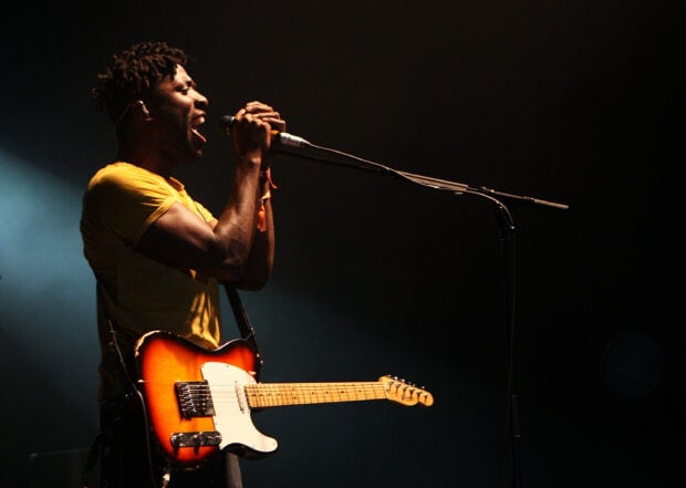 A member of Bloc Party band passionately singing on stage with a guitar, 2K Desktop Wallpaper