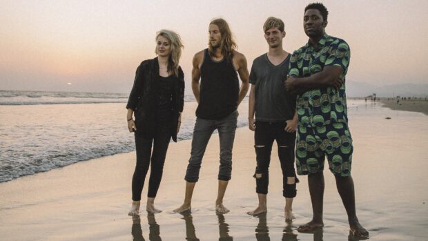 Bloc Party band standing barefoot on the shore with the ocean behind them, 2K Desktop Wallpaper