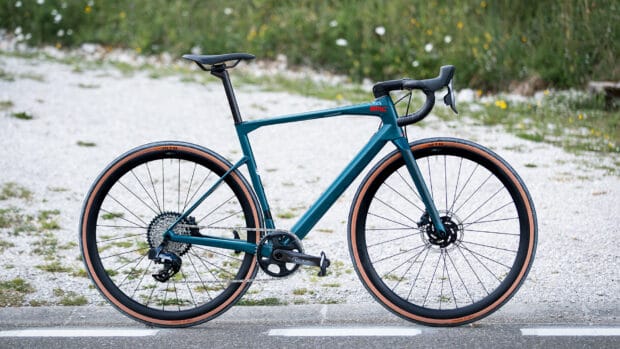 A sleek blue BMC bike stands on a gravel road surrounded by nature in full view, HD Desktop Wallpaper