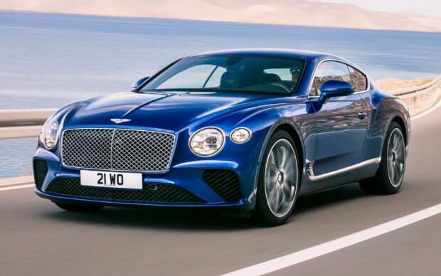 A blue Bentley Continental GT is driving along a scenic coastal highway with ocean views, HD Desktop Wallpaper