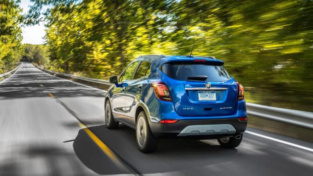 A blue Buick Encore drives smoothly down a tree lined highway in motion, 4K Desktop Wallpaper