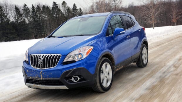 A blue Buick Encore drives through a snowy forest road with mud splashes on its body, 4K Desktop Wallpaper