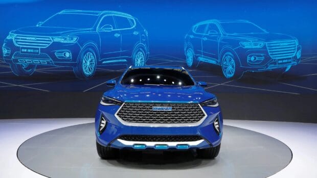 Blue Great Wall Motors car is displayed with two digital sketches in the background on a showroom floor, 2K Desktop Wallpaper