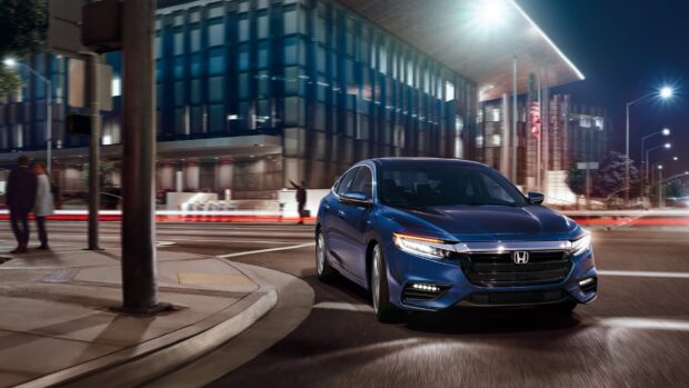 A blue Honda Insight is seen driving on city streets illuminated by streetlights at night, HD Desktop Wallpaper
