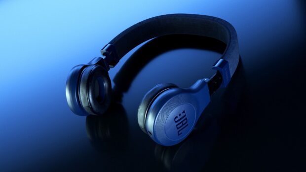A pair of blue JBL headphones resting on a shiny surface with a soft gradient background, HD Desktop Wallpaper