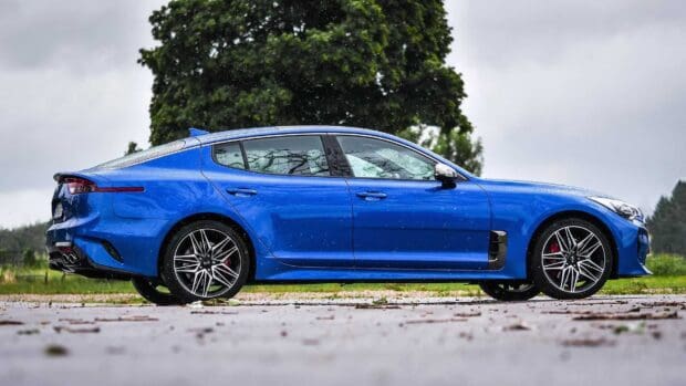 A blue Kia Stinger car is shown on a wet surface with raindrops during cloudy weather, HD Desktop Wallpaper