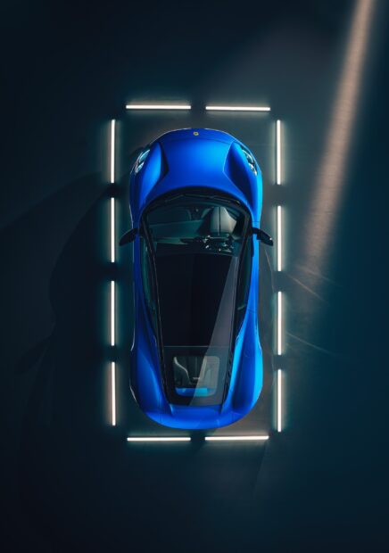 A blue Lotus Emira is illuminated by vertical lights in a dark setting, 2K Mobile Wallpaper