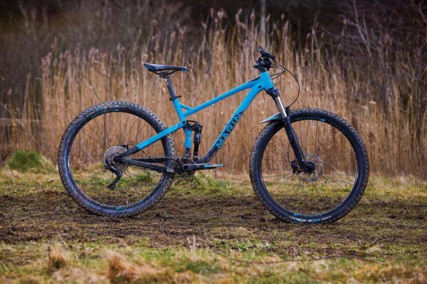 A blue Marin bike stands on muddy grass with tall dry plants behind it, 2K Desktop Wallpaper