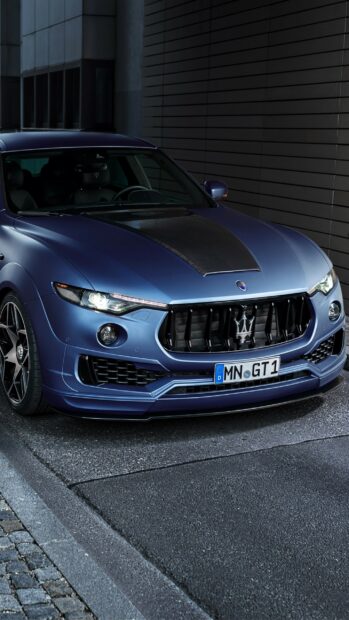 A blue Maserati Levante stands near a modern building with detailed design elements, 2K Phone Wallpaper