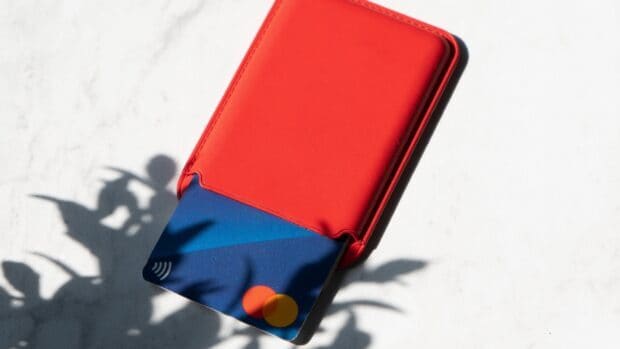 A blue Mastercard card partially pulled out from a red leather wallet on a white surface, HD Desktop Wallpaper