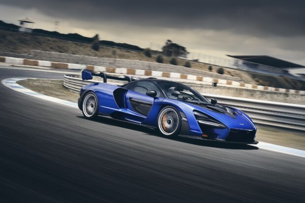 A blue McLaren Senna is speeding along a racetrack under a cloudy sky, HD Desktop Wallpaper