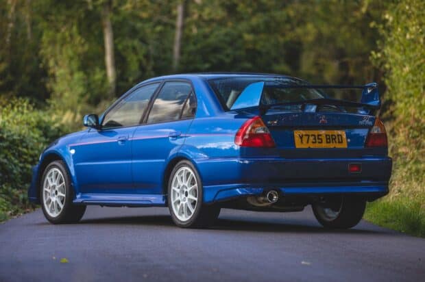 A blue Mitsubishi Lancer Evo car is parked on a road surrounded by green trees, HD Desktop Wallpaper