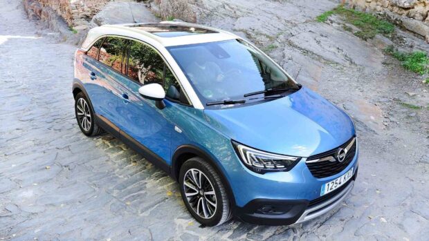 A blue Opel Crossland is parked on a cobblestone street surrounded by stone walls, HD Desktop Wallpaper