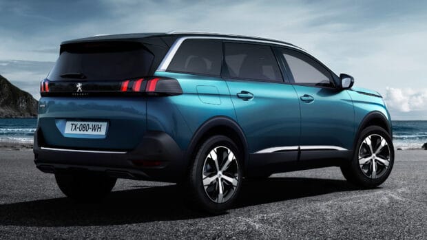 A blue Peugeot 5008 SUV is parked on a coastal road with ocean and mountains in the background, 4K Desktop Wallpaper