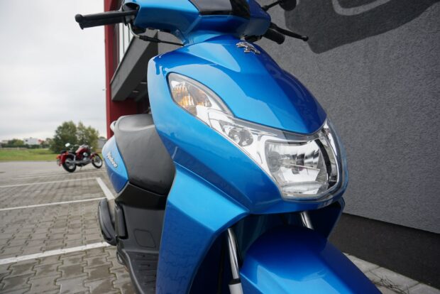 A blue Peugeot Kisbee scooter parked outside near a building on a cloudy day, HD Desktop Wallpaper