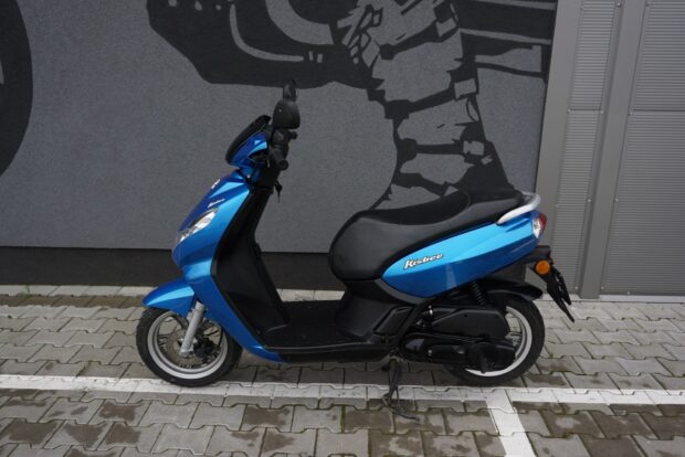 Blue Peugeot Kisbee scooter is parked along a tiled street with a mural behind it, HD Desktop Wallpaper
