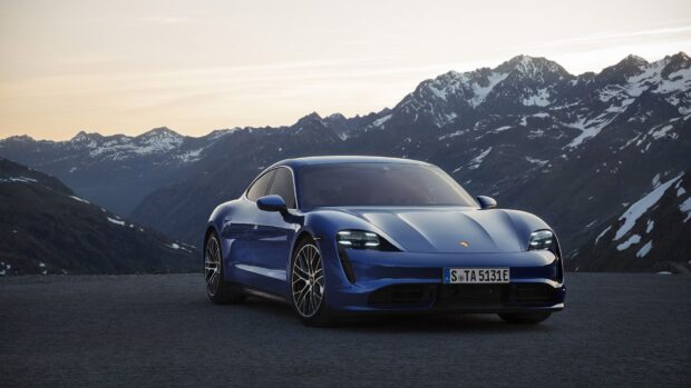 A blue Porsche Taycan is parked on a mountain road with snowy peaks in the background, HD Desktop Wallpaper