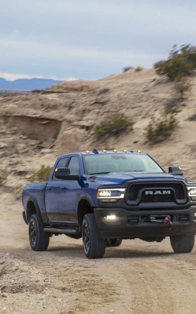 A blue Ram Truck is driving through a rocky desert area with hills in the background, HD Phone Wallpaper