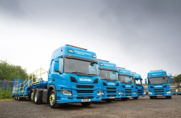 A lineup of blue Scania trucks is parked outdoors under a cloudy sky, HD Desktop Wallpaper