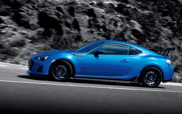 A blue Subaru Brz is driving fast along a winding mountain road, showing its sporty design, 2K Desktop Wallpaper