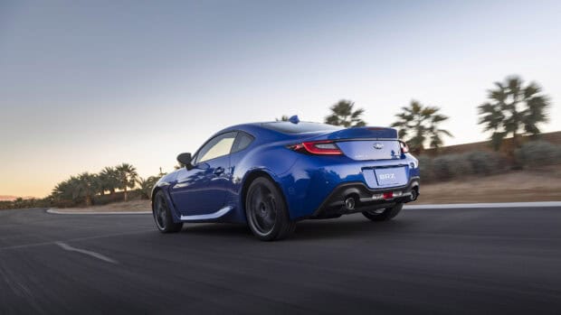 A blue Subaru Brz is driving on a winding road lined with palm trees during sunset, 4K Desktop Wallpaper