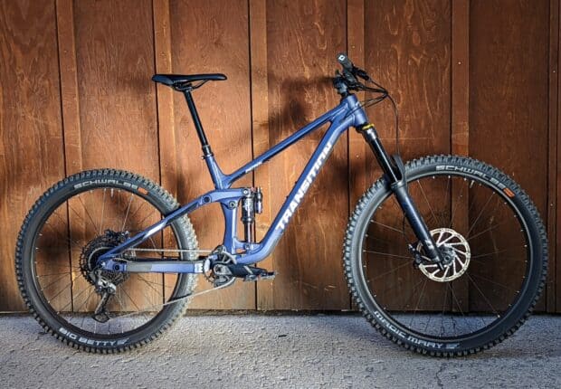 A blue Transition bike is placed sideways against a brown wooden wall, showcasing its full frame and tires, HD Desktop Wallpaper