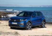 Volkswagen T Cross is shown on a sandy beach with the ocean and mountains in the background, 4K Desktop Wallpaper