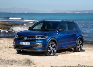 Volkswagen T Cross is shown on a sandy beach with the ocean and mountains in the background, 4K Desktop Wallpaper