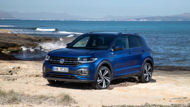 Volkswagen T Cross is shown on a sandy beach with the ocean and mountains in the background, 4K Desktop Wallpaper