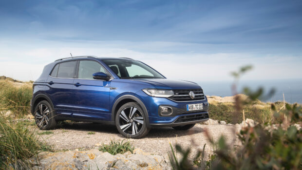 A blue Volkswagen T Cross is parked on a gravel road near the coast under a clear sky, 4K Desktop Wallpaper