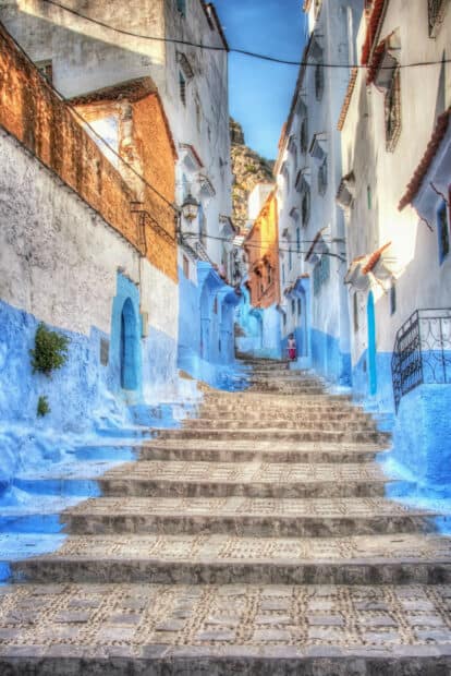 A narrow street with blue and white walls leads up stone stairs in Morocco, HD Phone Wallpaper