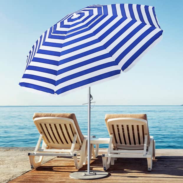 Two lounge chairs under a blue and white beach umbrella by the sea, HD Desktop Wallpaper