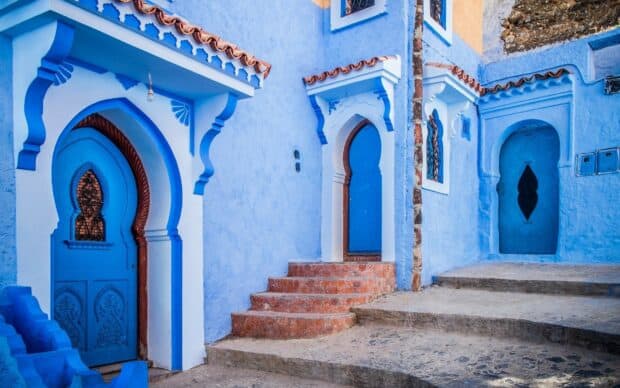 A peaceful Moroccan street features vibrant blue doors and decorative arches, HD Desktop Wallpaper