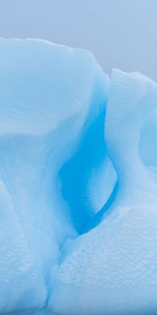 This glacier wallpapers 4K and HD shows a deep blue crevasse surrounded by smooth ice formations, HD iPhone Wallpaper
