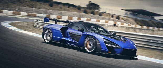A blue sports car races sharply around the curve on a professional race track, 2K Desktop Wallpaper