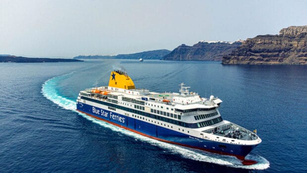 A Blue Star Ferries vessel moves through calm waters near rocky cliffs with a clear sky, HD Desktop Wallpaper