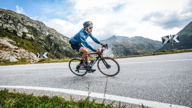 A cyclist rides a Bmc bike on a winding mountain road with scenic views, 2K Desktop Wallpaper