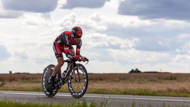 A cyclist rides a Bmc bike on an open road under a cloudy sky, HD Desktop Wallpaper
