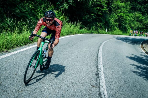 A cyclist rides a Bmc Bikes bike on a winding road surrounded by greenery, HD Desktop Wallpaper