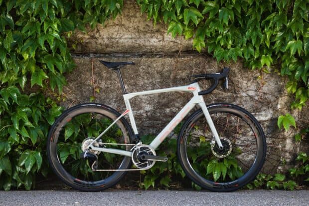 A sleek Bmc bike stands against a leafy wall in an outdoor setting, HD Desktop Wallpaper