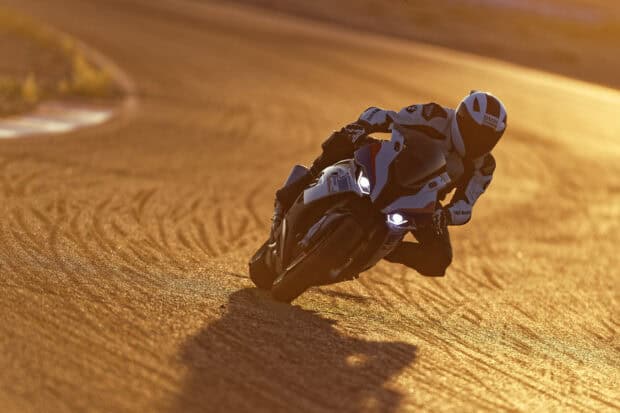 A Bmw M 1000 Rr is cornering sharply on a sunlit racetrack during sunset, HD Desktop Wallpaper