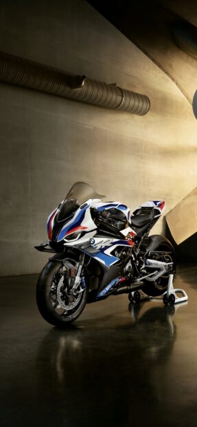 A BMW M 1000 RR is showcased in a modern garage with detailed design and colors, 2K Phone Wallpaper