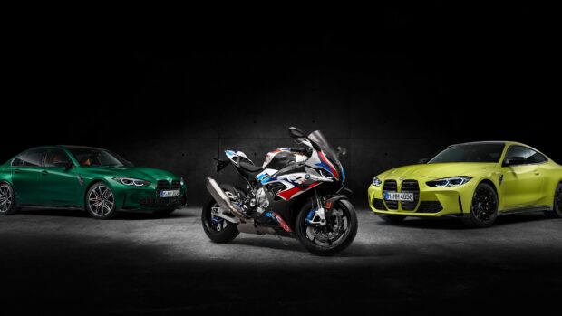A Bmw M 1000 Rr sports bike with racing decals is parked between two colorful vehicles in a dark setting, 4K Desktop Wallpaper